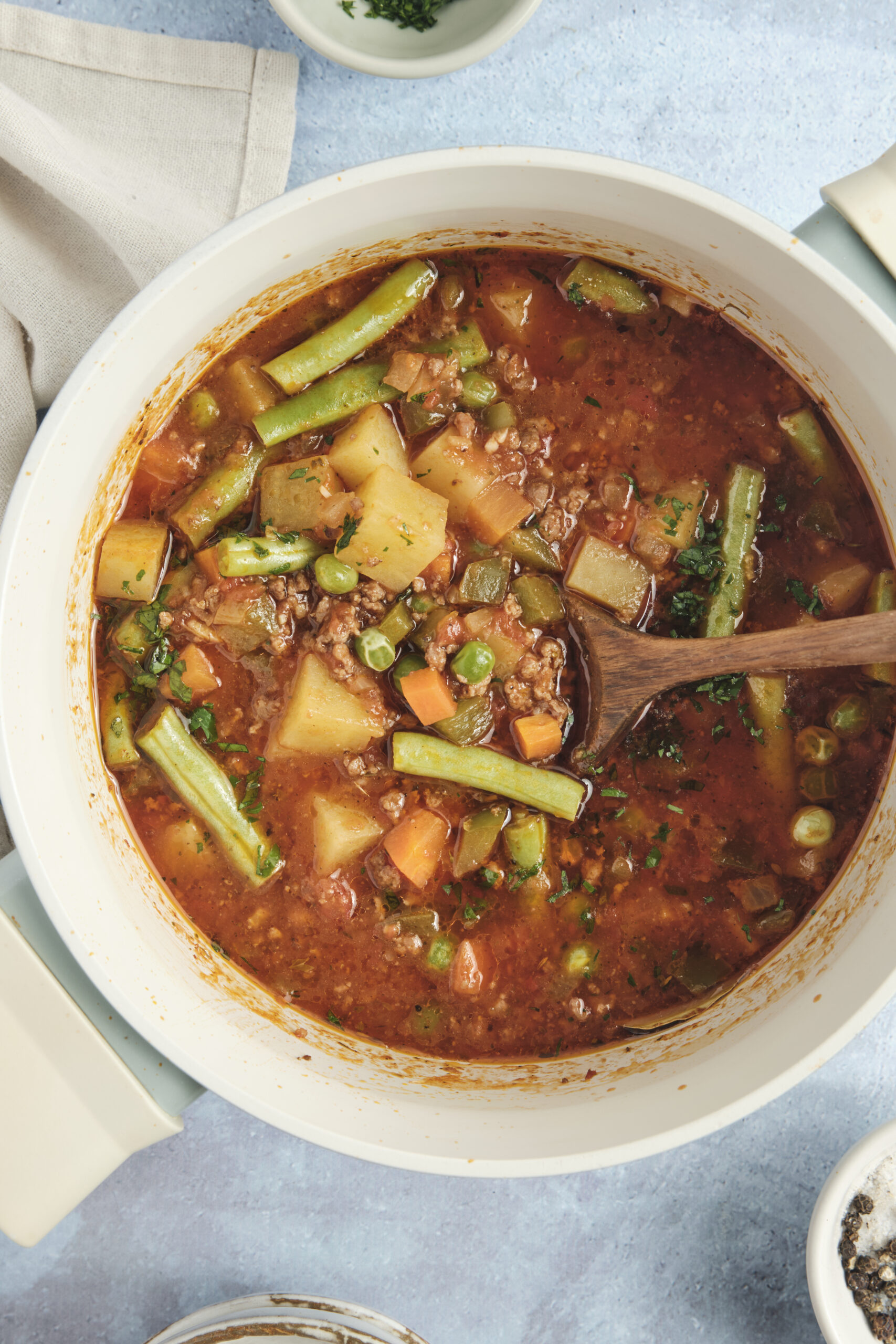 Hamburger Soup simmering in a white pot with ground beef, potatoes, and mixed vegetables.