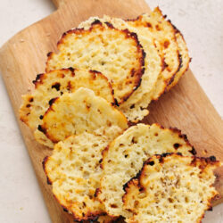 Golden brown cottage cheese chips seasoned with everything bagel seasoning on a wooden board.
