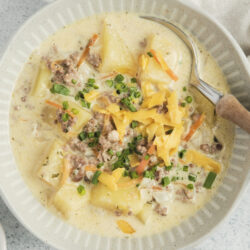 Crock-Pot Cheeseburger Soup in a bowl, topped with shredded cheddar and green onions.