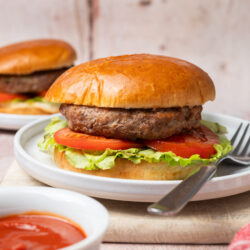 Meatloaf burgers on buns with lettuce and tomato, served with a side of ketchup.
