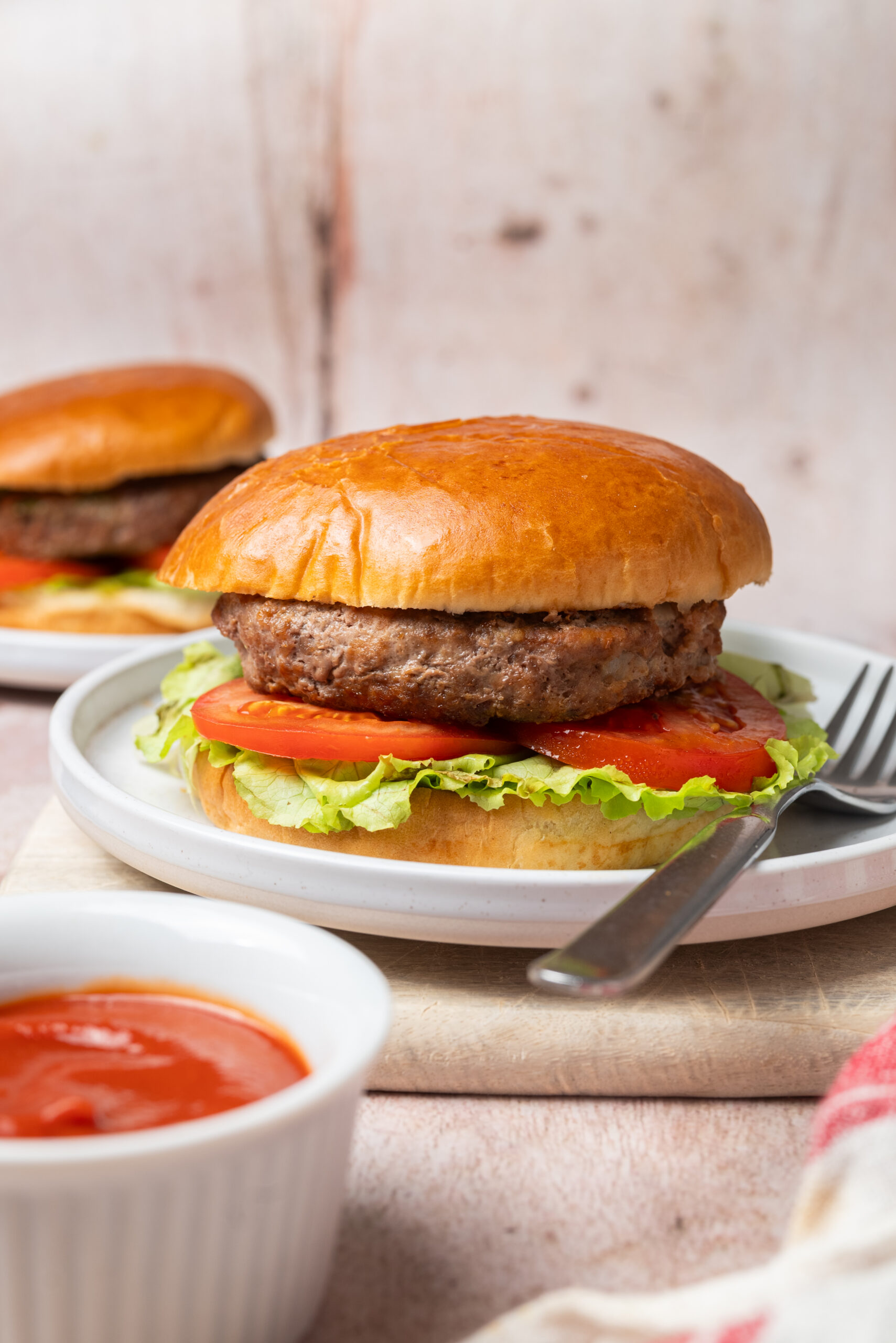 Meatloaf burgers on buns with lettuce and tomato, served with a side of ketchup.