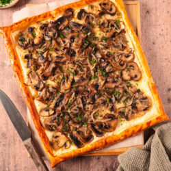 Mushroom tart with golden puff pastry, topped with saut&eacute;ed mushrooms, onions, and fresh parsley.