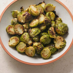 Roasted Brussels sprouts in a light gray bowl with a terracotta rim.