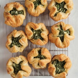 Golden brown spinach puffs filled with spinach and feta cheese on a wire cooling rack.