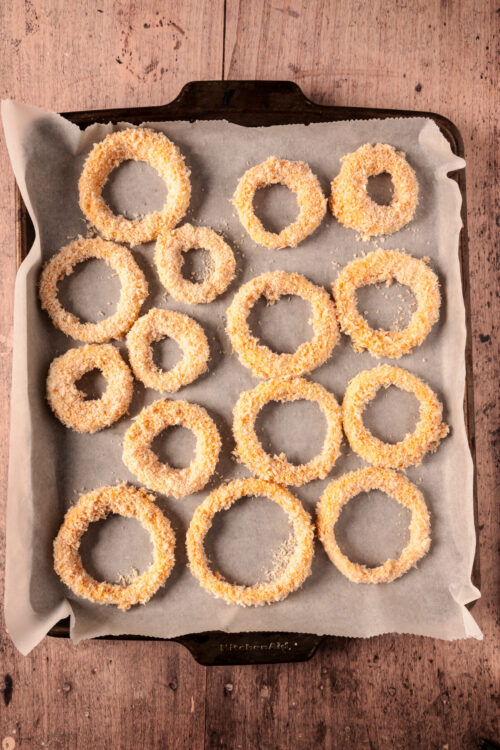 Breaded Baked Onion Rings ready for baking on a sheet.