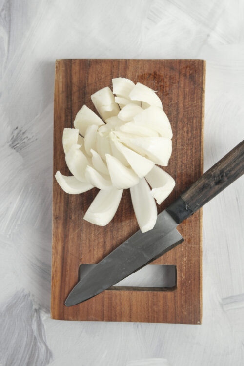 A blooming onion with fanned out petals on a cutting board.