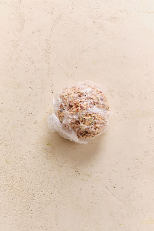 Cheese ball wrapped in plastic wrap, ready for chilling.