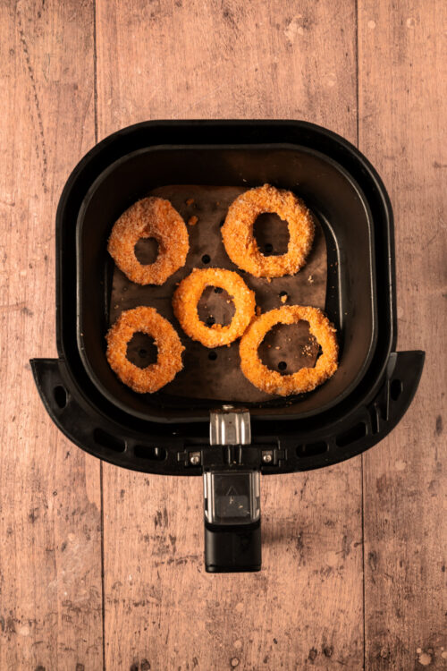 Arranging Keto onion rings in an air fryer basket.