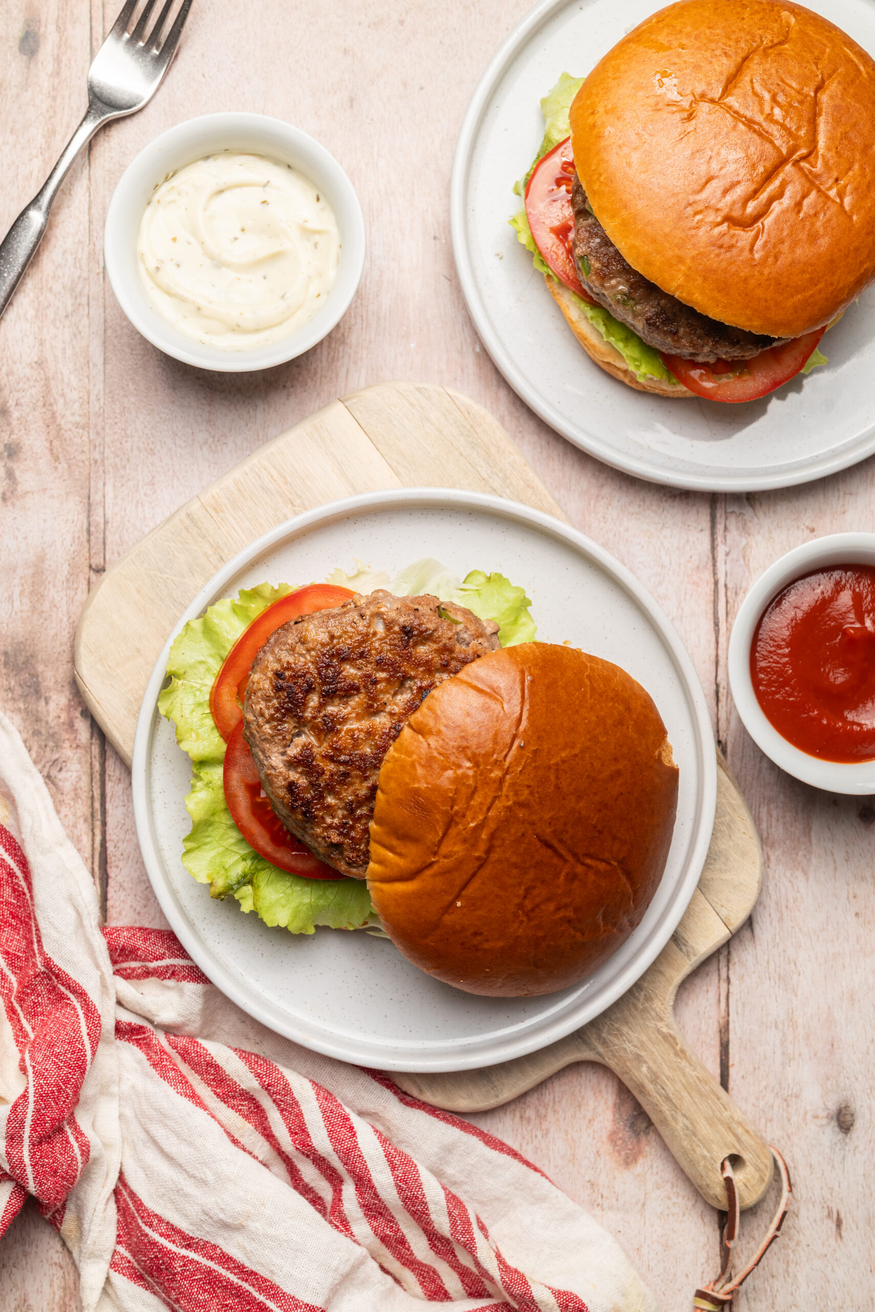 Two Meatloaf Burgers on buns with lettuce, tomato, ketchup, and a creamy sauce.