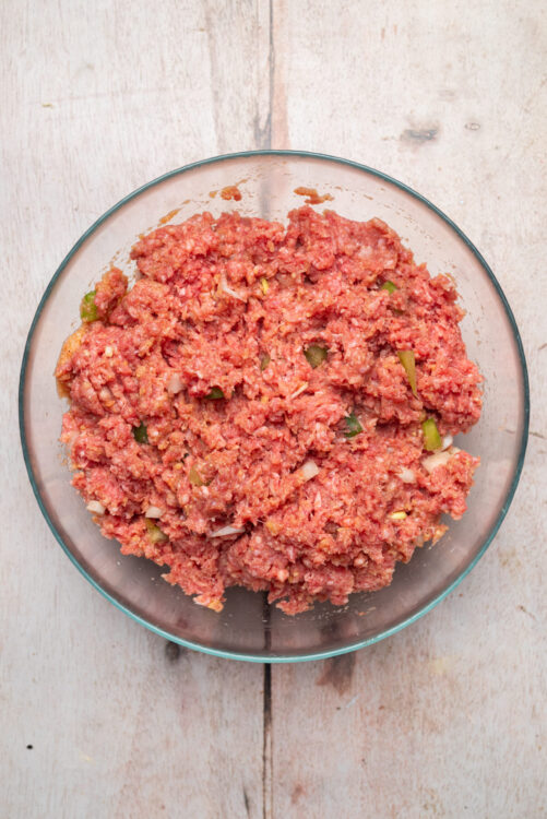 Combining lean ground beef, chopped onion, and bell pepper for Meatloaf Burgers.
