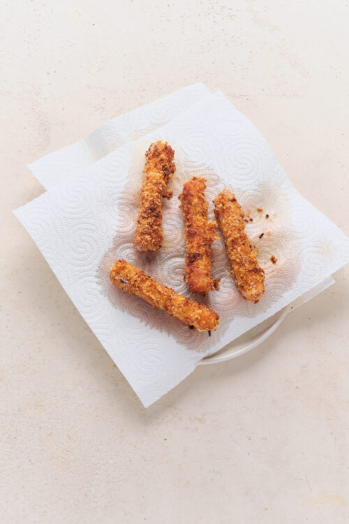 Fried mozzarella sticks draining on paper towels.