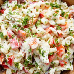 Chicken macaroni salad in a wooden bowl, garnished with fresh parsley.