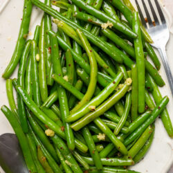 Garlic Green Beans served on a white platter, seasoned with minced garlic and red pepper flakes.