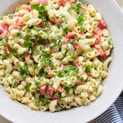 Macaroni Salad With Peas in a large bowl, topped with fresh parsley.
