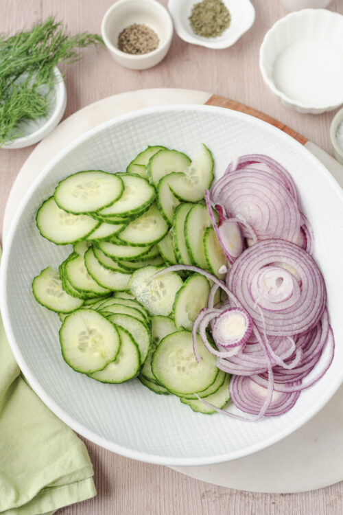 Thinly slicing cucumbers and red onion for cucumber and onion salad.
