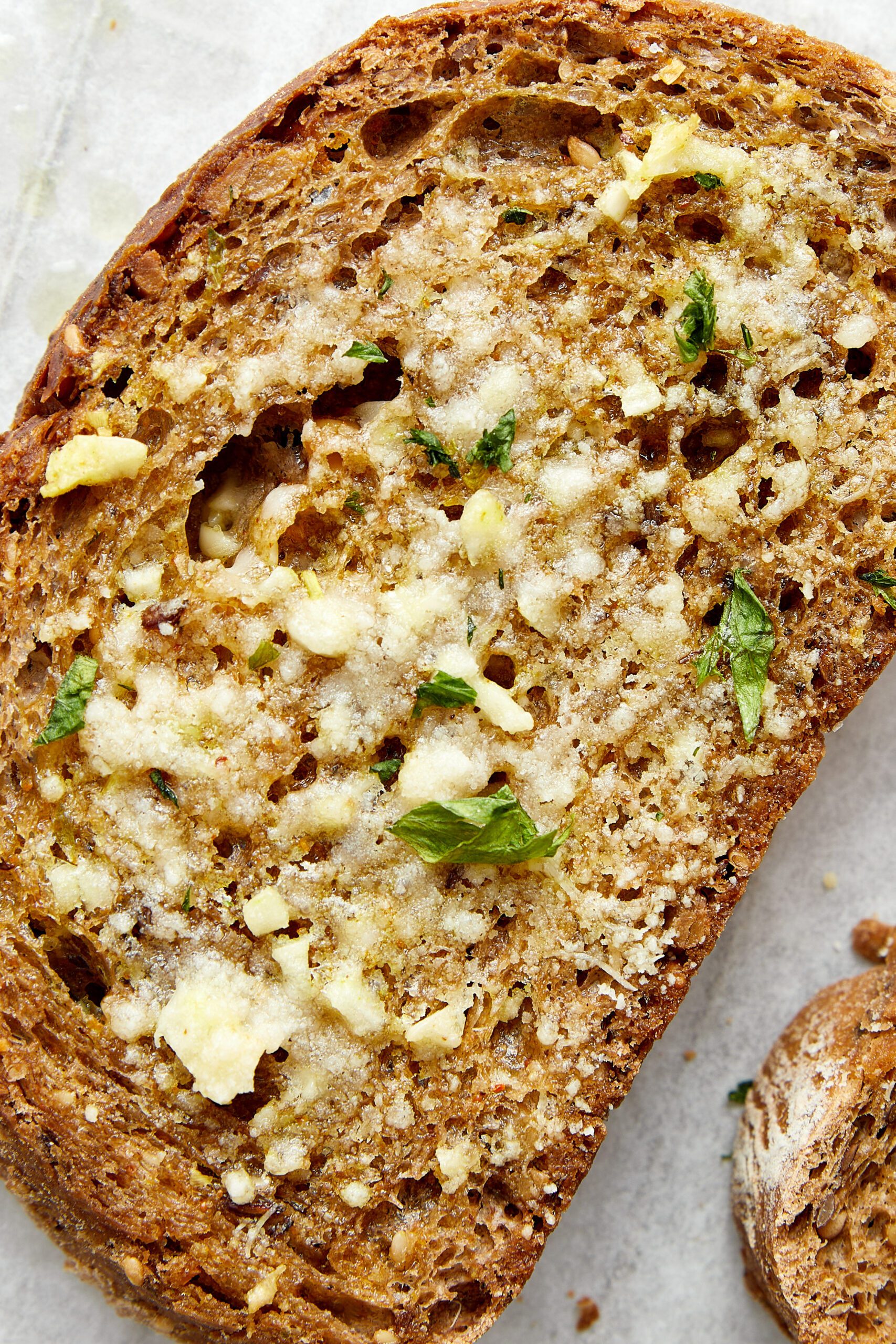 Toasted garlic toast slice, spread with garlic butter, minced garlic, and fresh parsley.