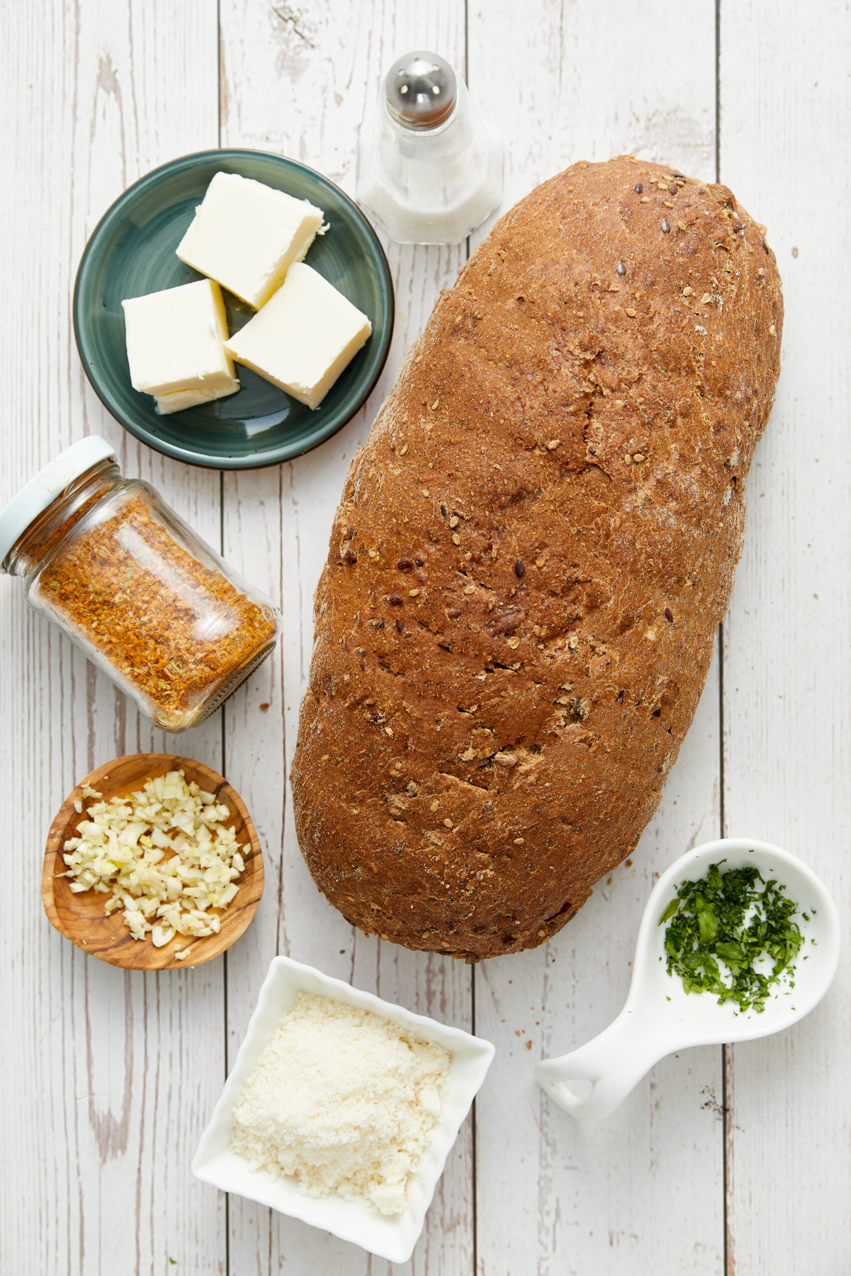 Ingredients for garlic toast recipe: hearty bread, butter, minced garlic, salt, Italian seasoning, Parmesan cheese, and fresh parsley.