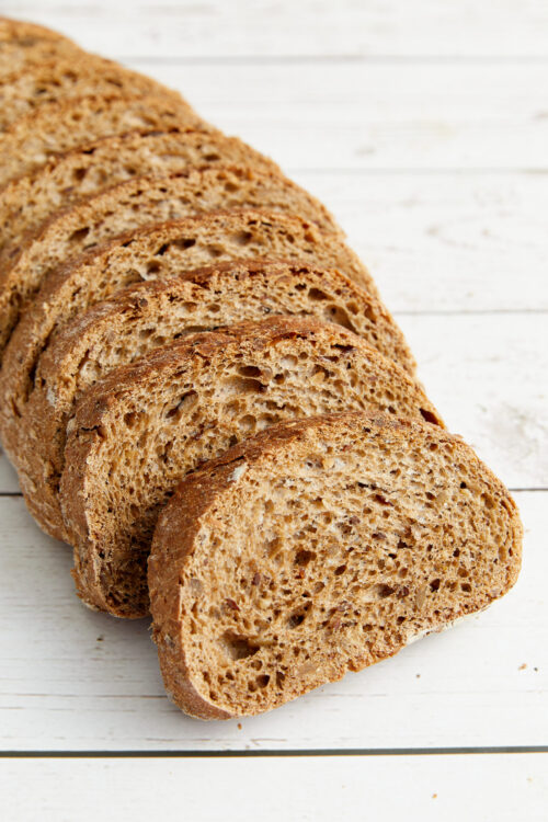 Cutting a loaf of hearty bread into thin slices for garlic toast.