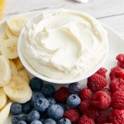Cool Whip Fruit Dip in a white bowl, surrounded by fresh bananas, blueberries, and raspberries.