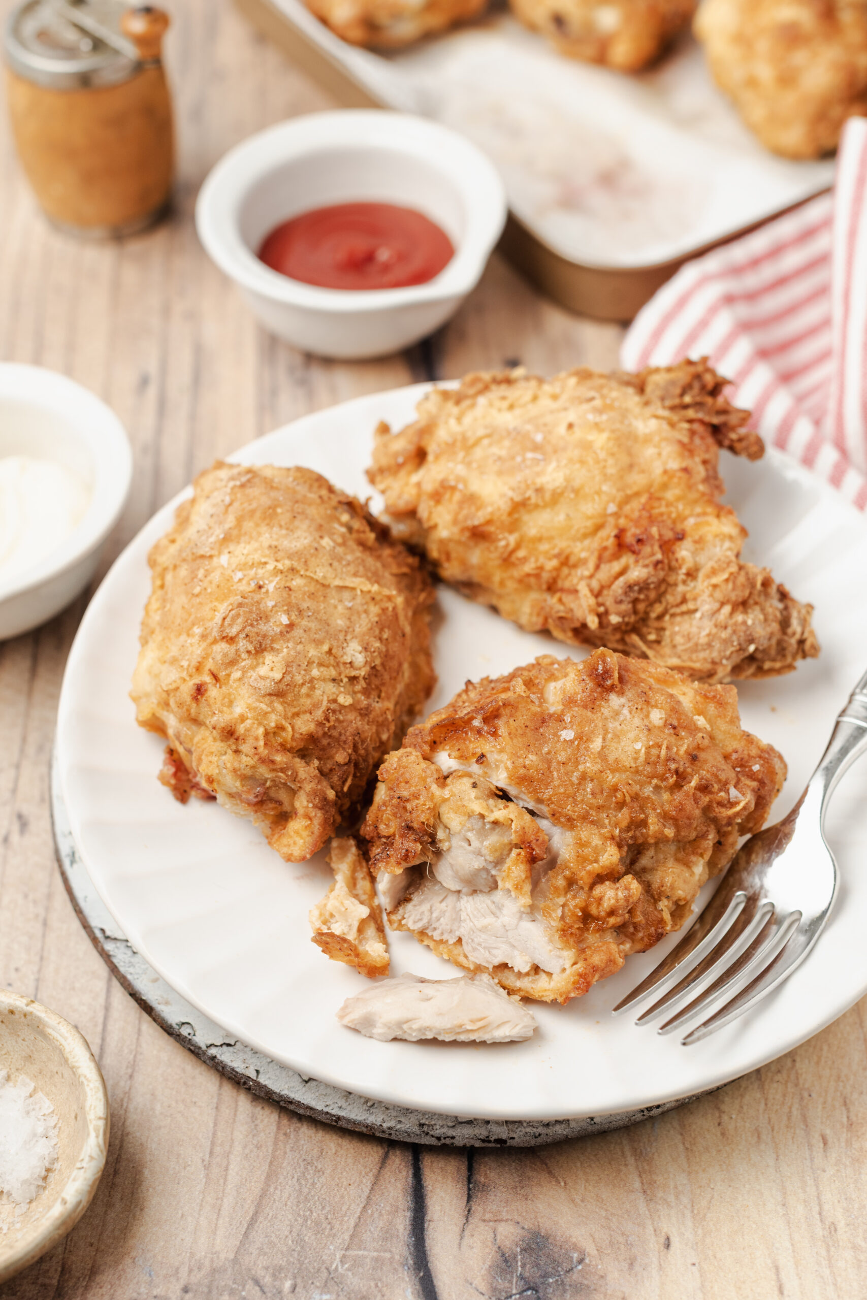 Golden-brown fried chicken pieces on a white plate, with one piece broken open.