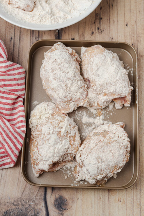 Coated chicken pieces resting on a tray for Fried Chicken Recipe.
